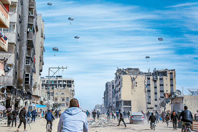沙城的巴人上周五跑到街上拾取空投的人道救援物資。
