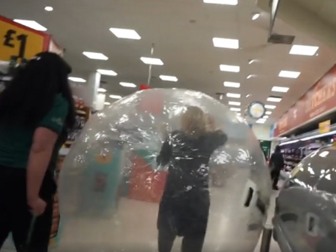 英國女子怕受感染躲進充氣球逛超市。(網圖)