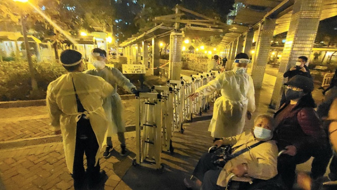 警員及政府工作人員在元州邨元盛樓拉起圍欄，進行需圍封強檢。