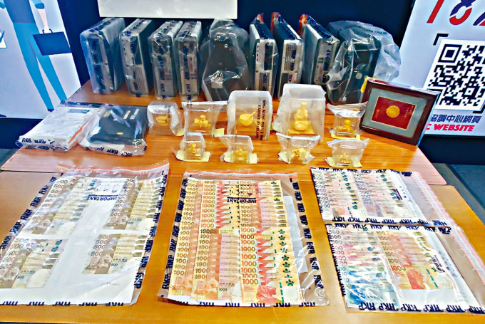■警方展示检获的电脑、现金及金色的装饰品等证物。
