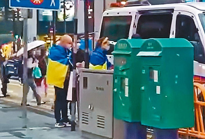 身披烏克蘭國旗的男女登上警車。