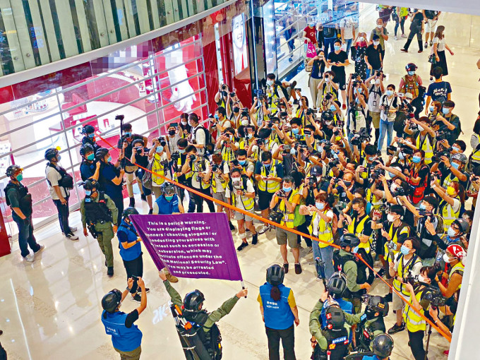 ■示威者在刑點商場聚集及高叫「光復香港」口號，警員高舉紫旗警告各人涉違《港區國安法》。