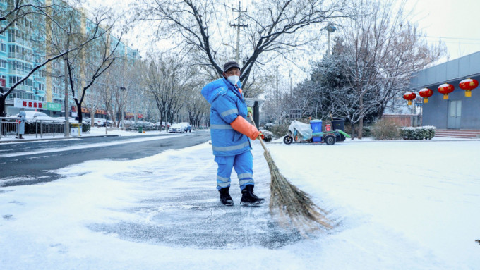北京市内工人忙于扫雪铲冰。新华社