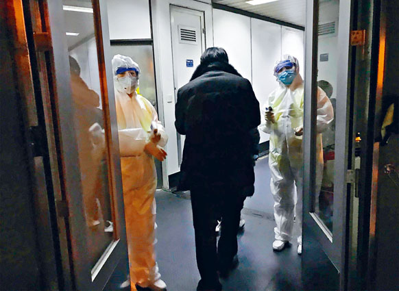 北京机场昨日有穿上保护衣的衞生官员在闸口等候检查由武汉入境的旅客。