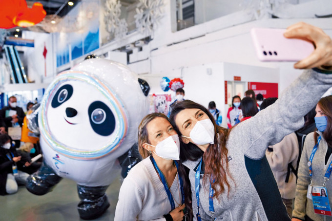 去年北京冬奧期間，外媒記者與冰墩墩合影。
