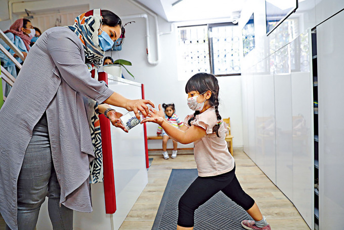 ■德黑蘭幼稚園學生回校時以搓手液消毒。