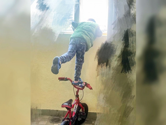 男童踩在单车上，半身探出窗外张望，情况非常惊险。「生仔要考牌系列」Facebook图片