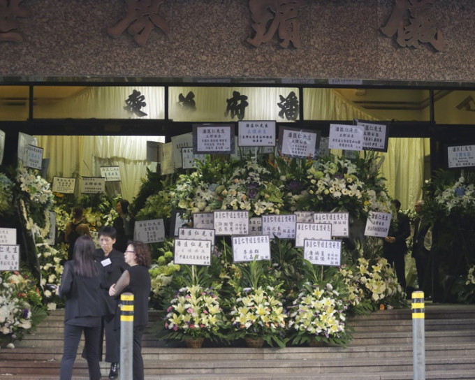 殯儀館外放滿寫有「主懷安息」的花籃。