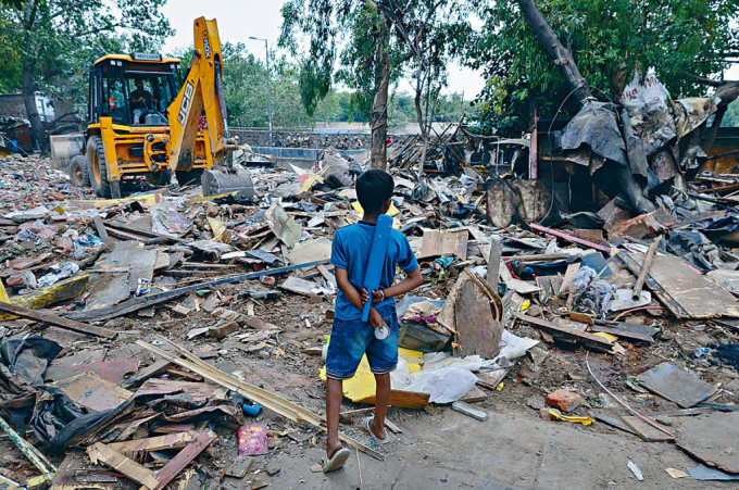 新德里簡塔營貧民窟的一個孩子，看着推土機剷平居所。