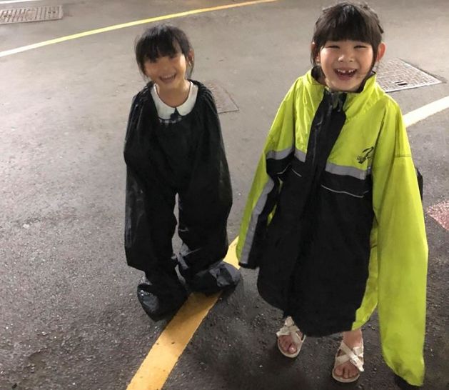 父亲巧妙地将雨裤和雨衣，让两名女儿分开穿上。网图