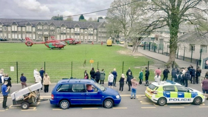网传照片显示紧急服服直升机停在学校草坪，家长在围栏外焦急等候。 X