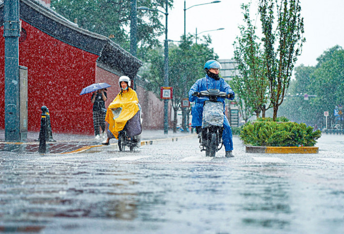 北京市民昨天在雍和宫大街冒雨骑行。