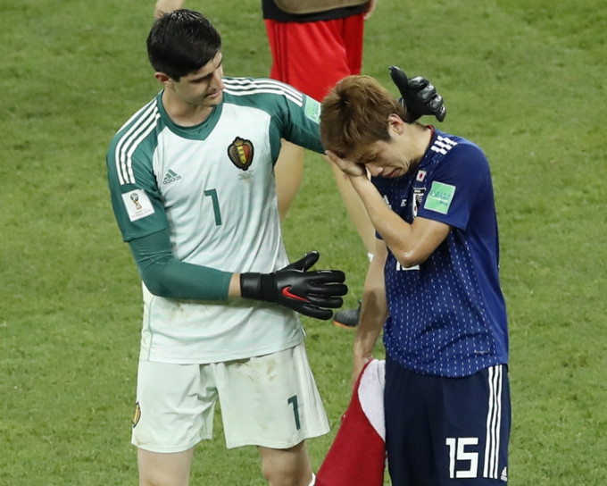 日本前锋大迫勇也握着毛巾拭泪，比利时门将泰拔高图尔斯拍拍他的头安慰。AP