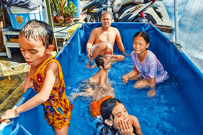 馬尼拉居民在街邊臨時搭建的浴池中消暑。