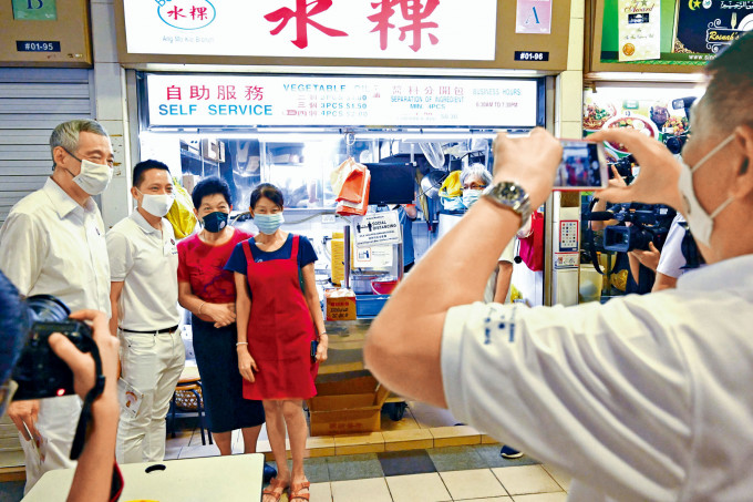 总理李显龙（左）上周五落区为人民行动党拉票时，与民众合照。