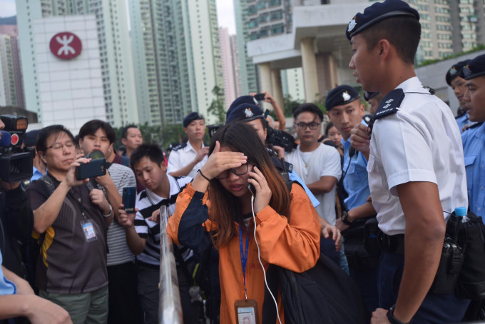 女領隊（橙衫者）其後被警察查牌後，護送上巴士離開。梁譽東攝