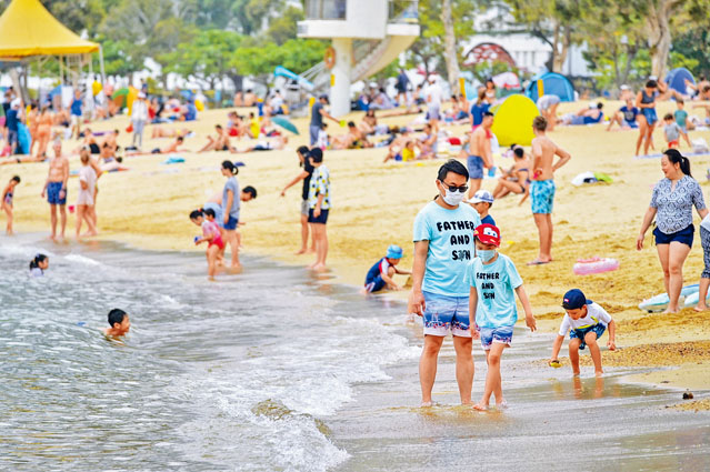 ■近日天氣稍回暖，市民往淺水灣「玩水」，仍不忘戴着口罩。