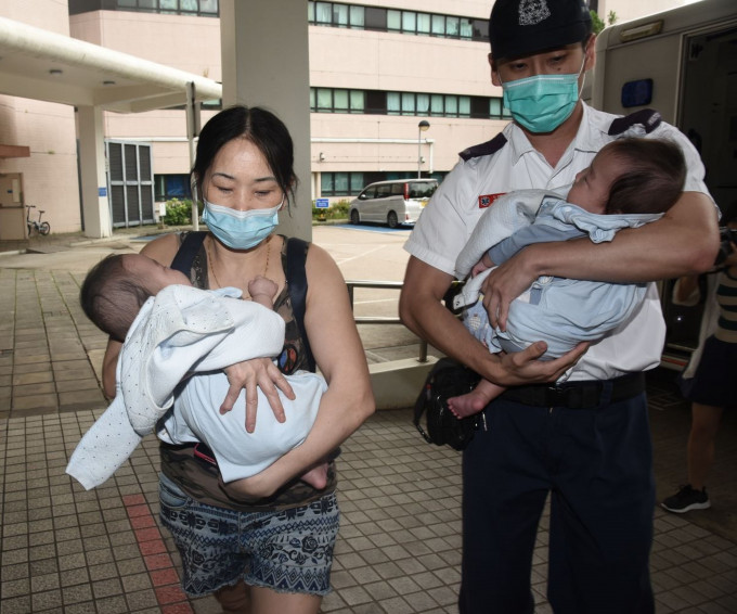 孪生男婴昨日分别由祖母(左)及男警手抱送院检验。