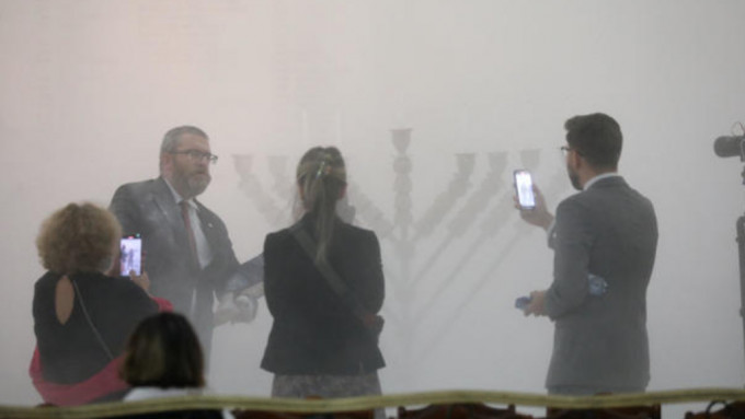 布劳恩(左二)用灭火筒狂喷犹太光明节的烛台。路透社