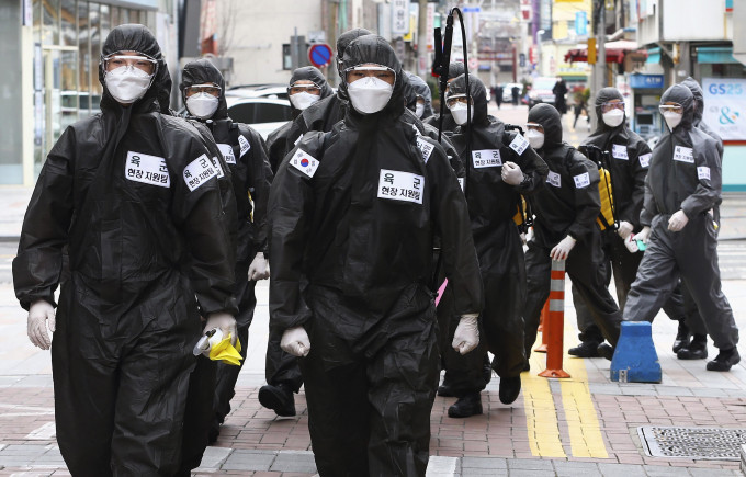 在大邱市街头，有穿著保护衣的南韩军方人员喷洒消毒剂。 AP图