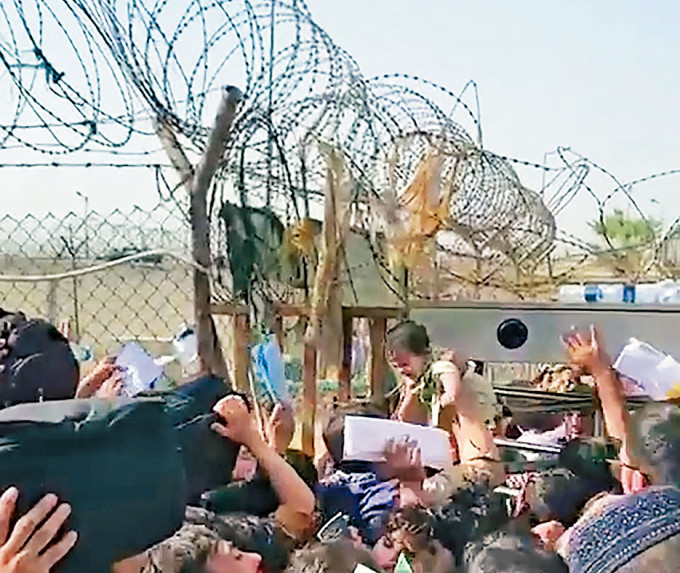 喀布尔机场有民众要把婴儿高举，交给铁丝网另一边的英兵。