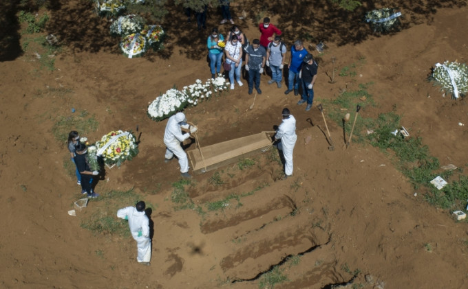 有无人机拍摄到，工作人员埋葬一名死者时穿上了防护服。AP