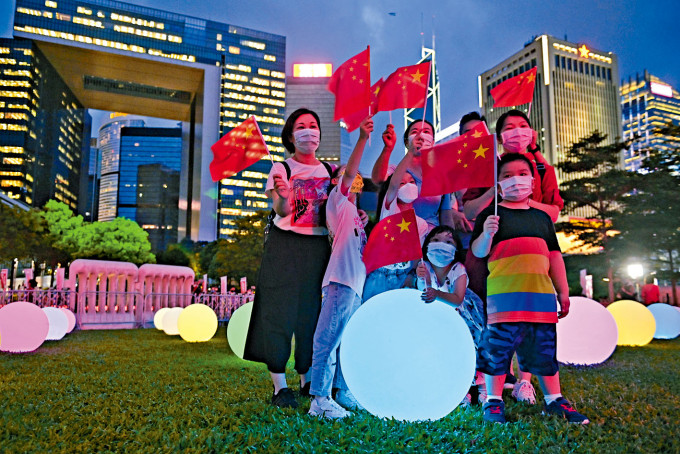 ■市民帶同國旗和區旗到添馬公園欣賞「光影3D耀維港」表演。