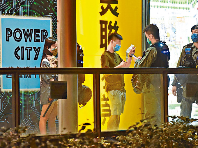 警方在商場範圍向違反「限聚令」人士發出告票。