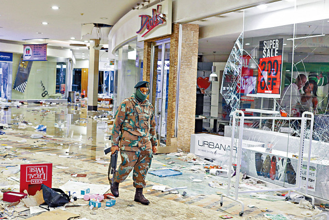 南非索韋托一個購物中心遭搶掠和破壞，軍人昨檢視損毀情況。