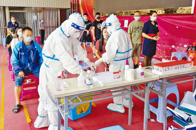防疫人員在瑞麗市為居民進行採樣檢測。　