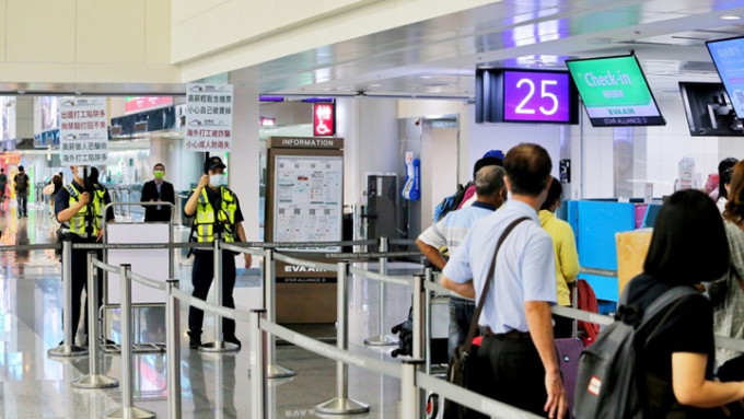 台湾近日出现诱骗民众到柬埔寨的求职陷阱，警员要在机场举牌提醒出境人士防范。中时图片