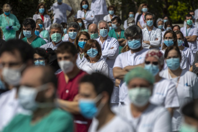 西班牙大批前線醫護為一名感染新冠肺炎殉職的外科主任默哀1分鐘。AP圖