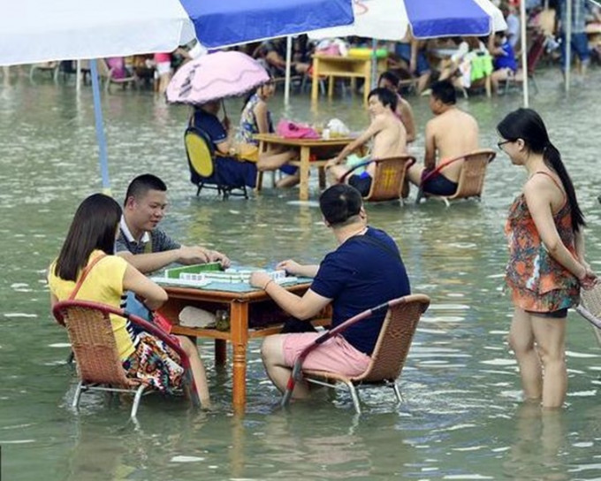 市民赤脚浸泡在清凉的水中打麻雀消暑。