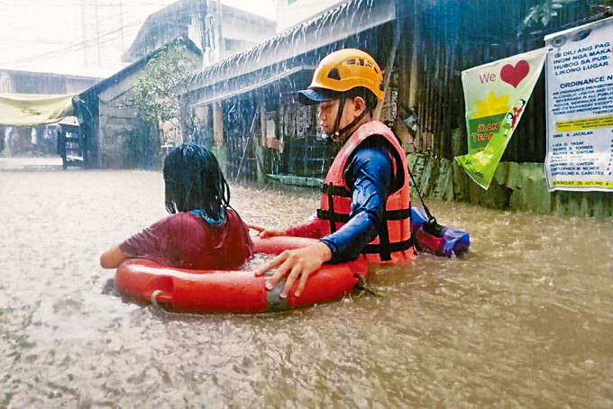 ■菲律宾救援人员周四在南部卡加延德奥罗市，协助被困洪水的女孩。