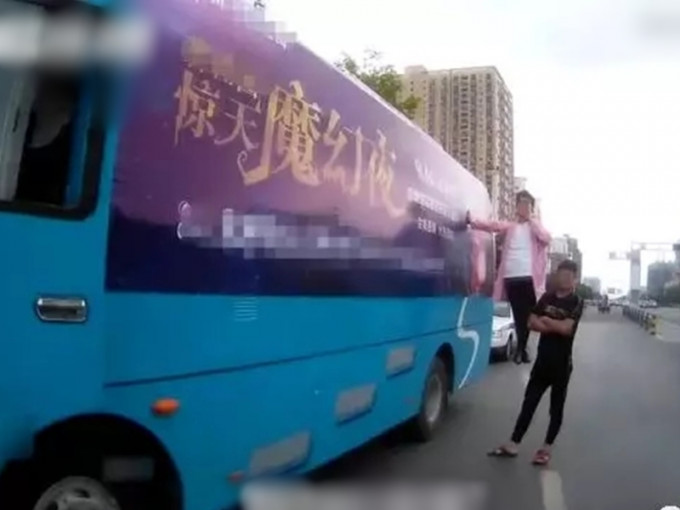 徐州一辆大巴在闹市区行驶，车外挂著一名男子。　网图