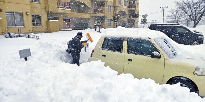 北海道北见市一男子昨日在停车场清理积雪。