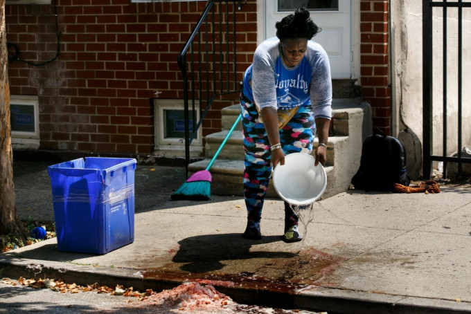 美国费城街头昨夜发生枪击案，一名女子清理街上血迹。网上图片