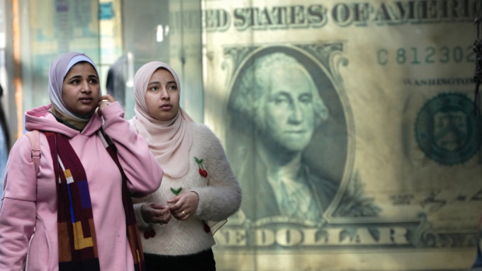 埃及民众途经一张美元纸币巨型海报。 美联社