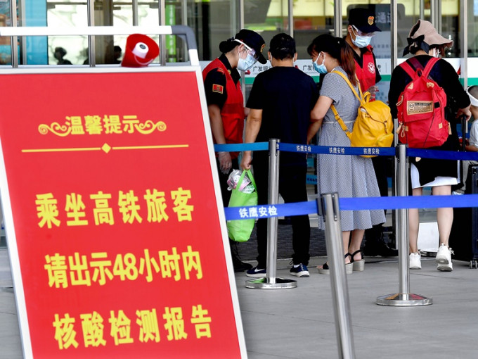 郑州东站工作人员在查验进站旅客的核酸检测结果。新华社