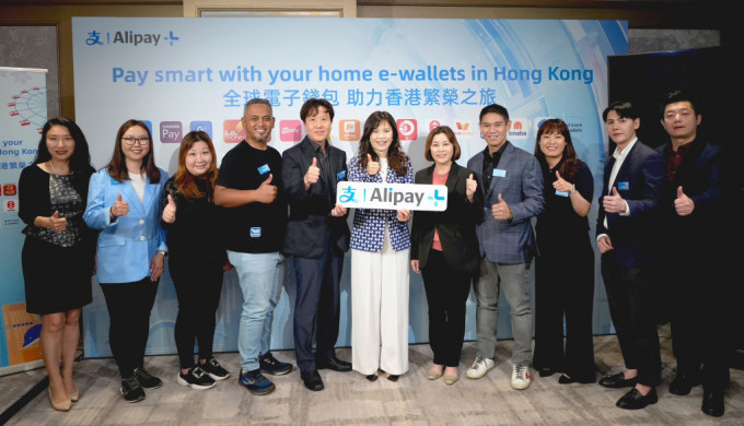 香港旅发局副总干事叶贞德女士(右五)、Shilla Travel Retail (HK) 董事总经理Kang San Ho先生(左五)与AlipayHK CEO兼蚂蚁国际大中华区总经理李咏诗小姐(中)以及国际主要支付软件负责人一起，庆祝Alipay+携多国电子钱包来港服务游客。