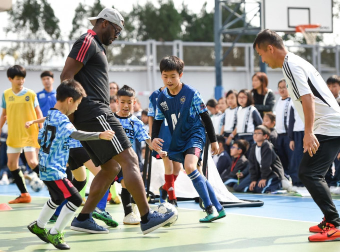 沙夏與李偉文及約百名師生，齊踢小型足球比賽。馬會圖片