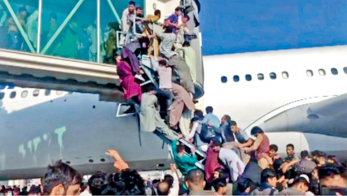 喀布尔国际机场数以百计阿富汗人周一拼命爬上登机桥，企图登上一架客机飞往国外。　