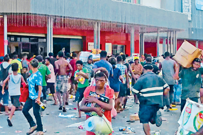 巴布亞新畿內亞首都莫爾斯比港周三爆發騷亂，暴民抱着從商店搶來的物品離開。
