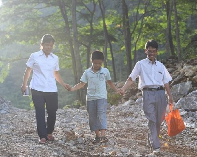 兒子農好佶拉著媽媽去山坳去迎接爸爸回家。圖:新華社