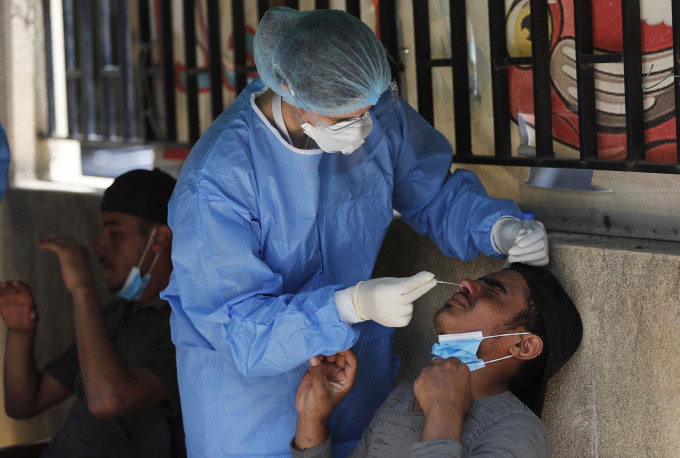 一名护士在孟加拉贝鲁特对一名工人进行病毒检测。 AP