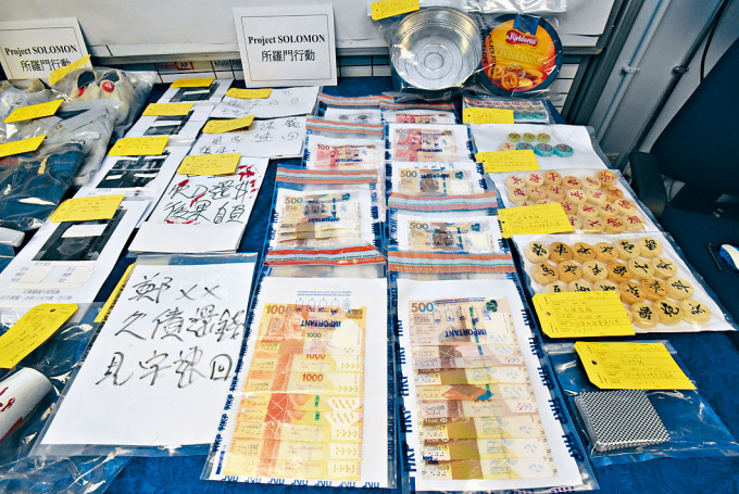 ■警方展示檢獲的大批證物，其中追債大字報附有債仔及親友姓名及資料。