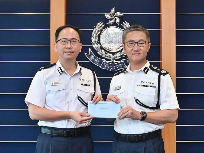 警務處處長蕭澤頤（右）頒授委任狀予新任香港輔助警察隊副總監梁世光（左）。政府新聞處圖片
