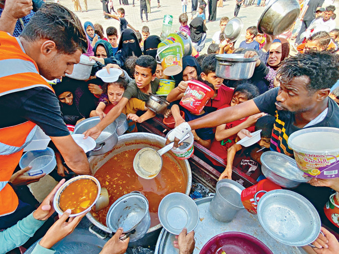 在加沙南部拉法市一间学校内避难的巴人，领取义工派发的食品。