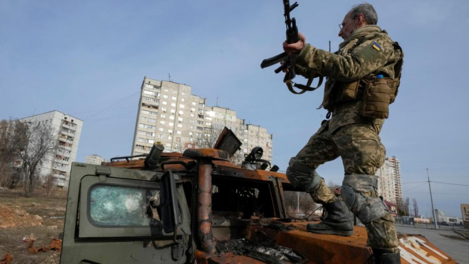 一名乌克兰士兵站在被摧毁的俄罗斯装甲运兵车上。AP