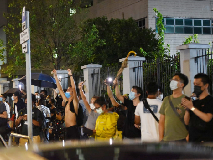 《苹果日报》支持者在大楼外举起手机，亮起闪光灯。